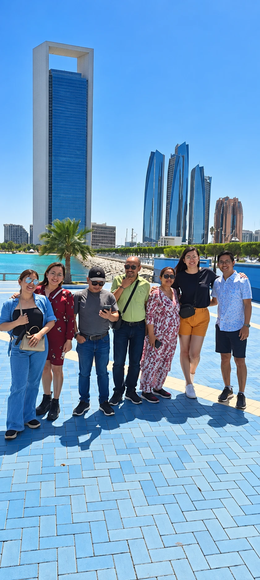 Guests posing on the blue waterfront promenade with the Abu Dhabi skyline behind them