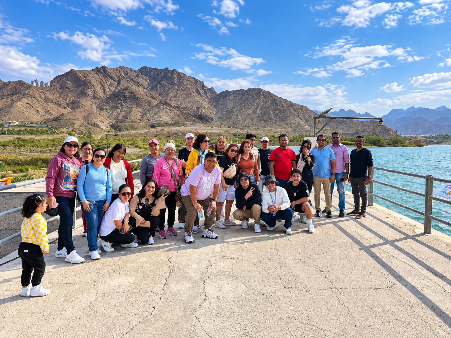 Group of guests on the Hatta Dam with the Hajar mountains and turquoise lake behind