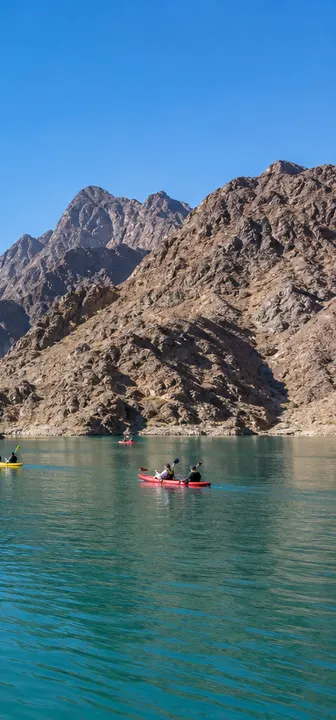 Kayaks on the turquoise water of Hatta Dam between the Hajar mountains