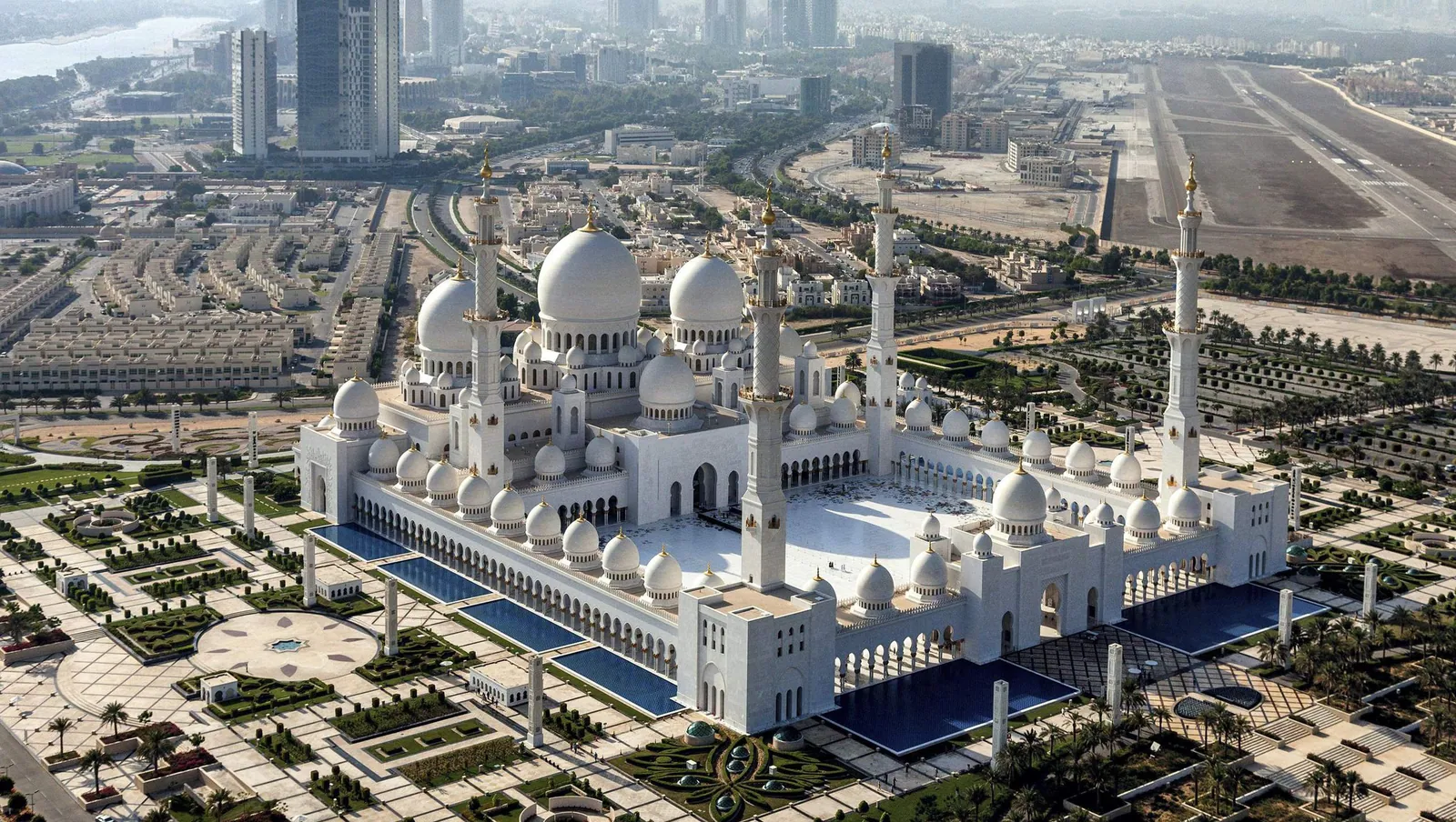Sheikh Zayed Grand Mosque from above, with its white domes, minarets and blue reflecting pools